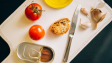 Tomatoes, bread, and sardines arranged for Catalán toast preparation.