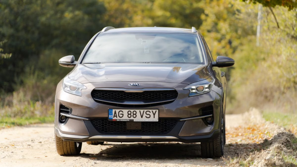 Front view of a Kia car parked on a countryside road during autumn.